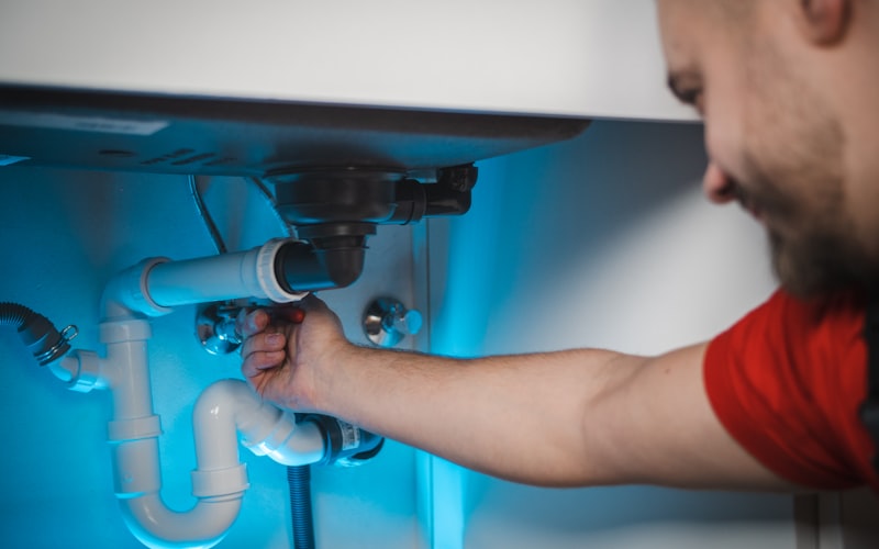 Plumber repairing residential pipes under sink